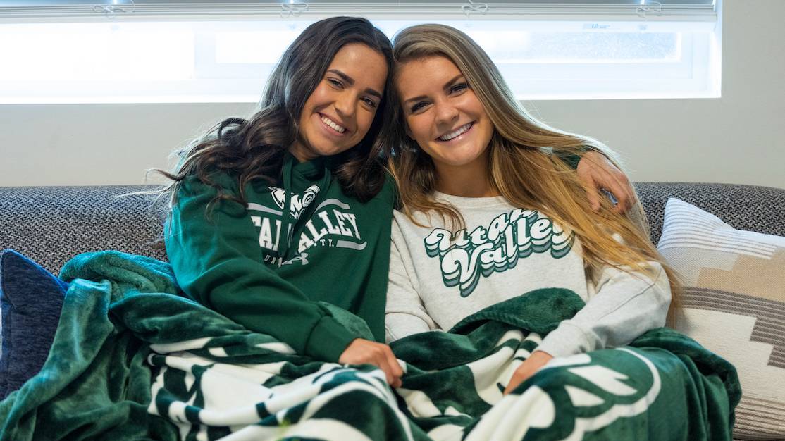 two roommates sitting on a couch next to eachother