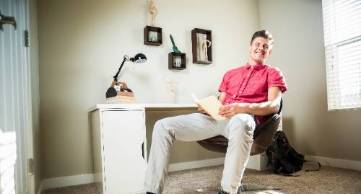 male student sitting at desk in housing complex