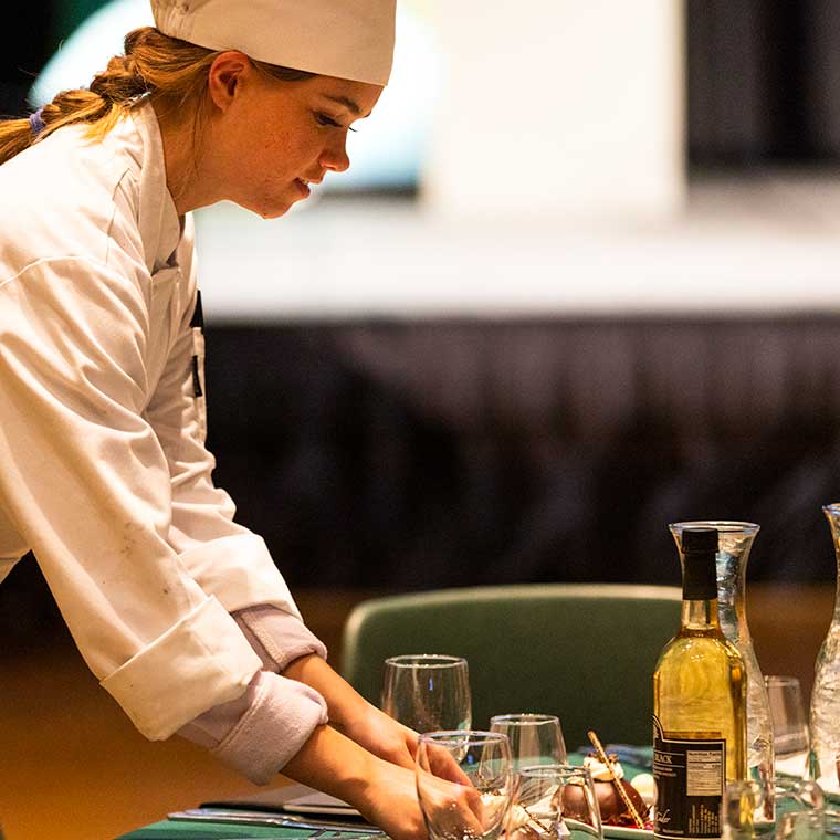 Culinary tudent prepares tables at the 'Awards of Excellence'