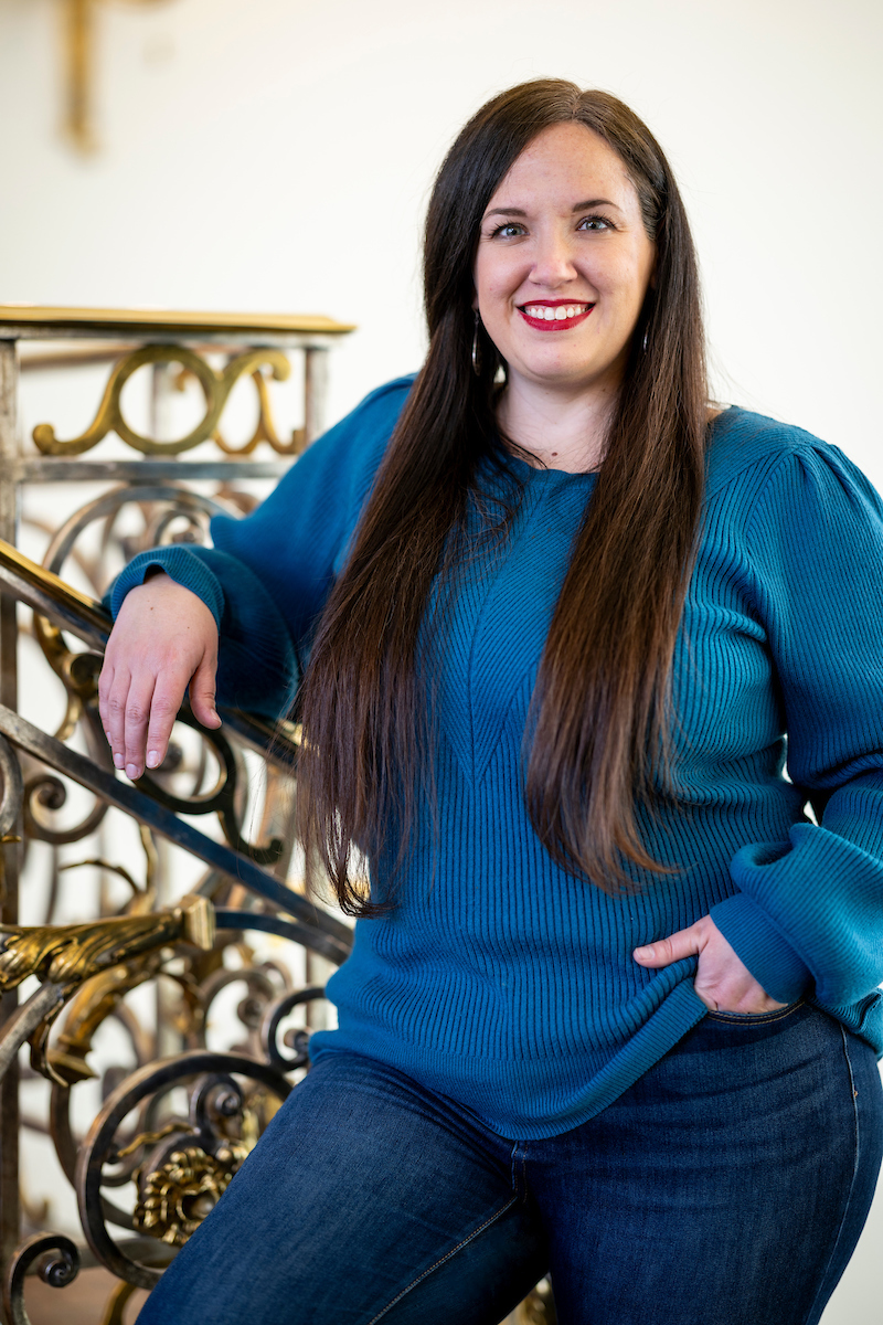 Person in a blue sweater leaning on a decorative railing.              