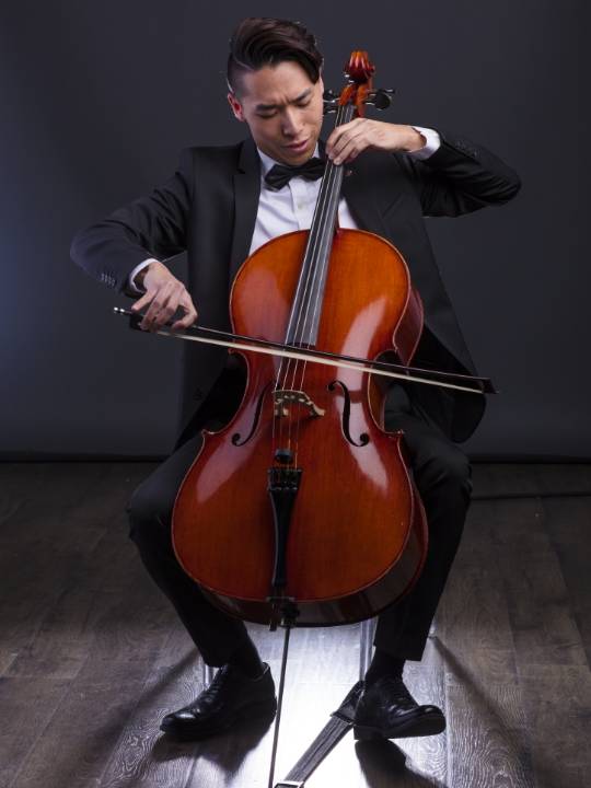 Person in black suit playing a cello