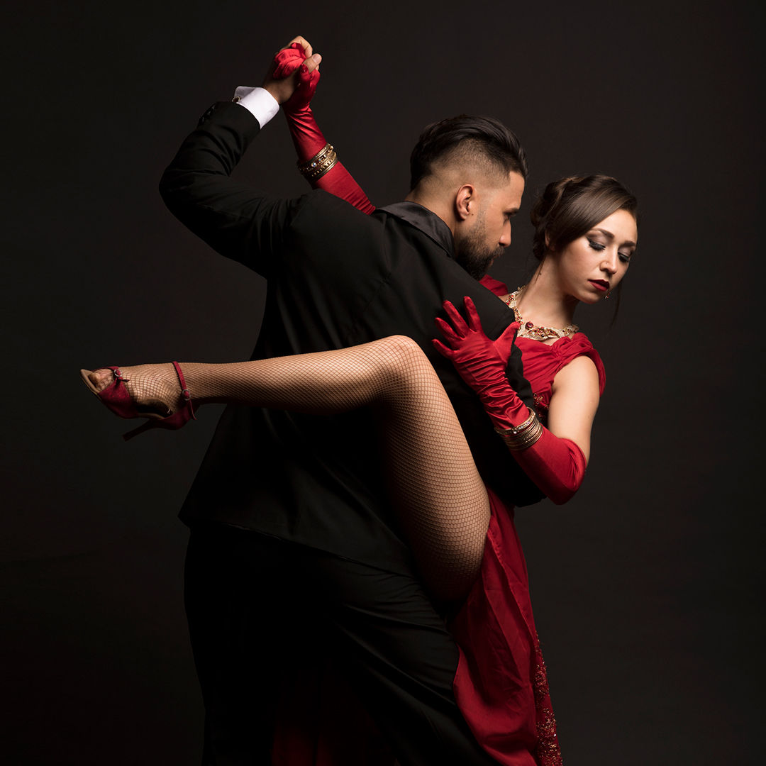 A man and woman dancing in elegant attire with swirling mist behind them.              