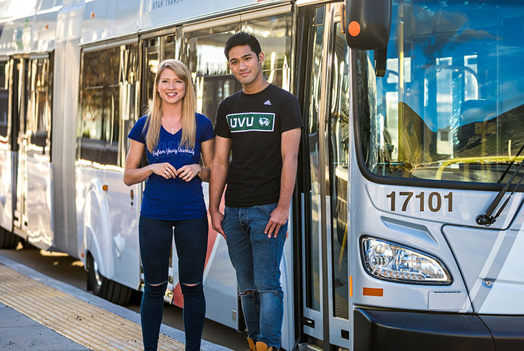 A male and female student standing in front of UVX bus