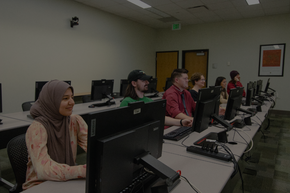 Image of students seated for a lecture with laptops in front of them