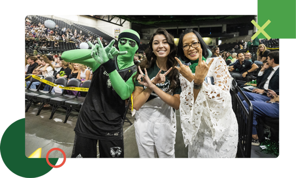President and student showing the UVU hand sign, made by putting up your pointer figer and pinky to make 2 "U" shapes and then crossing your arms to make the "V".