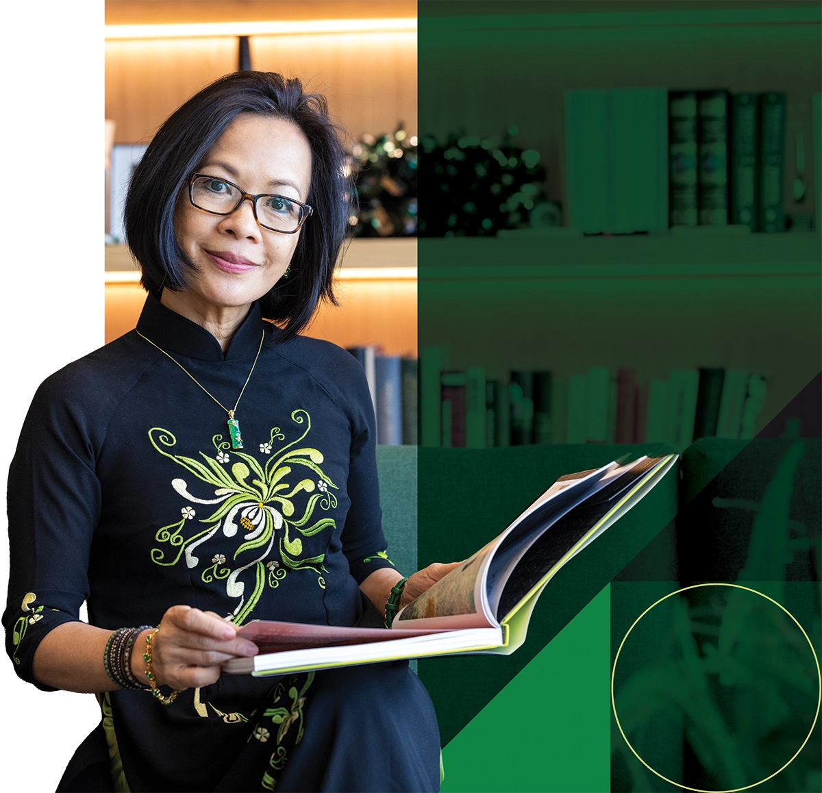UVU President Astrid S. Tuminez, wearing a black dress, smiles in her office, holding a book. 