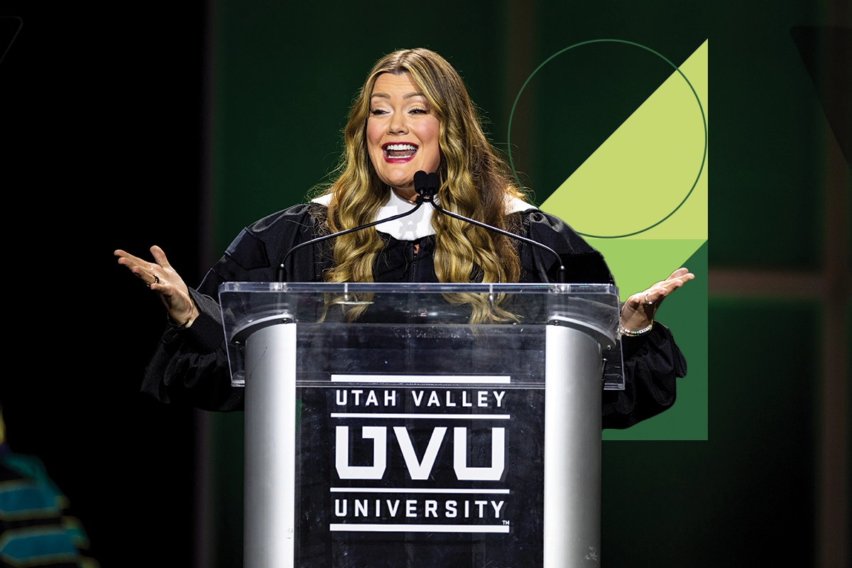Jamie Kern Lima, the keynote speaker for UVU’s 2024 commencement ceremony, speaks to the Class of 2024 at a podium while wearing black regalia. 