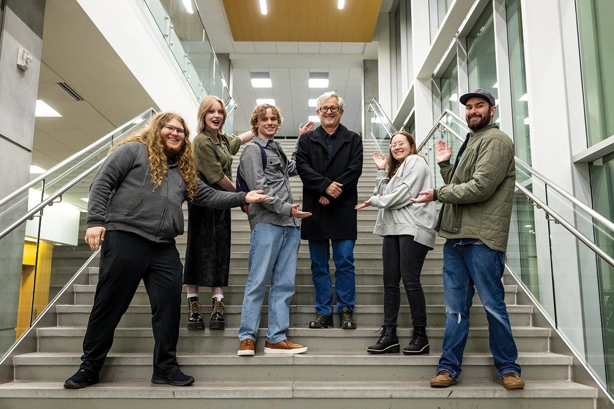 Students from the UVU-FanX Studios Writer’s Room pose on stairs on UVU’s Orem Campus with Hollywood screenwriter Ed Neumeier.