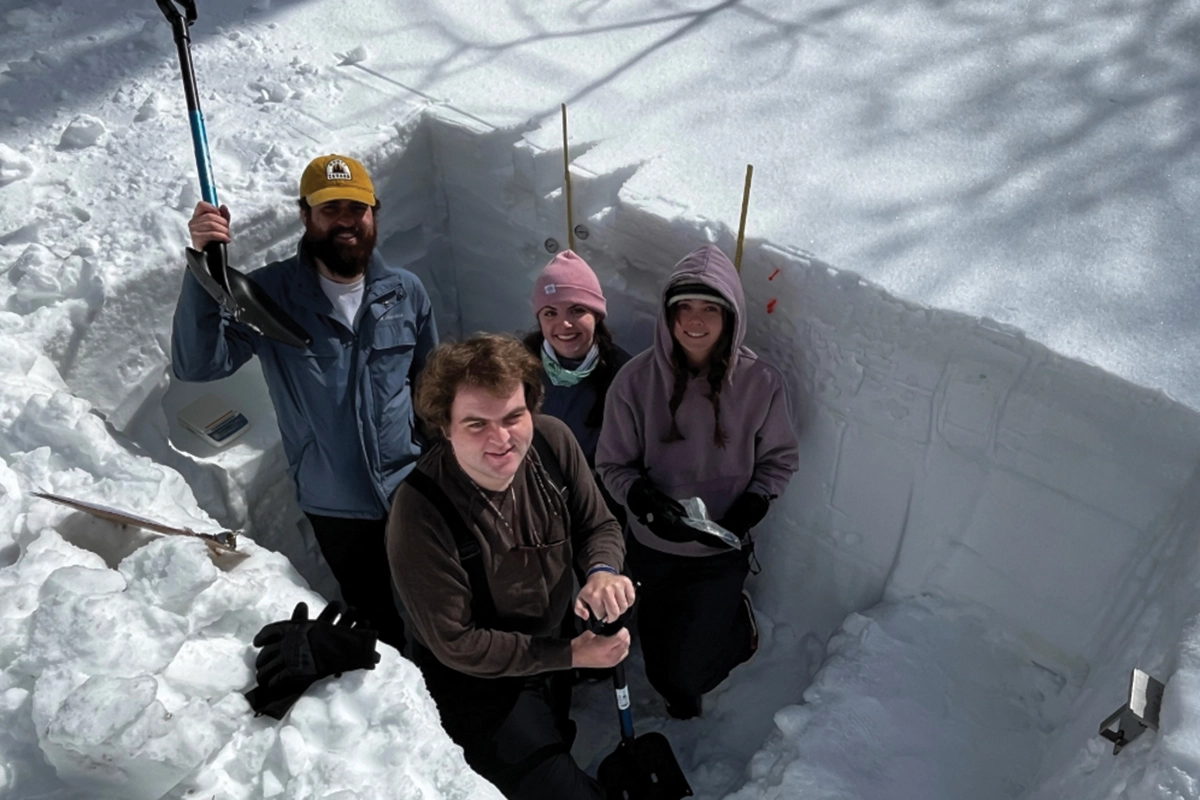 Four UVU students studying water resource research at Sundance Ski Resort smile at the camera while standing in the snow.
